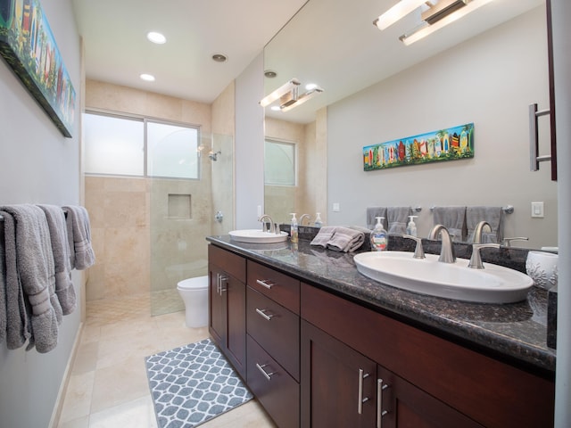 bathroom with double vanity, tile patterned floors, toilet, and a tile shower