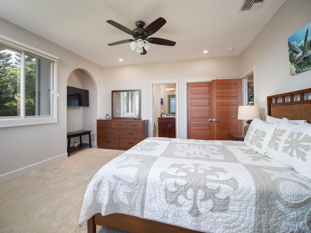 bedroom featuring ceiling fan, connected bathroom, and light colored carpet