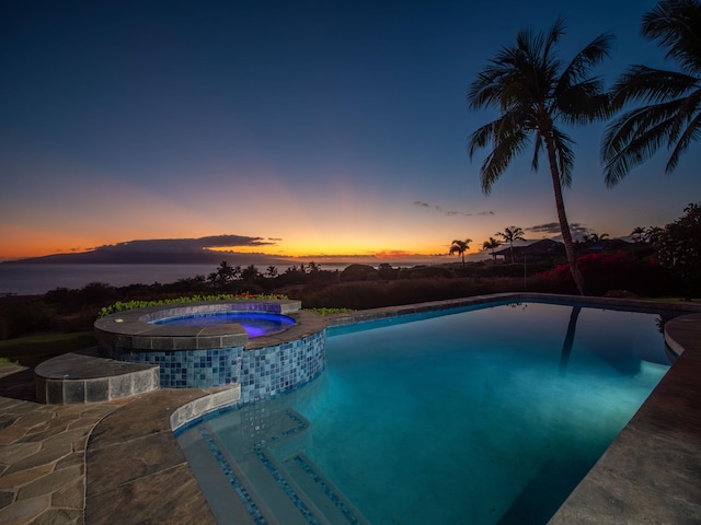 pool at dusk with an in ground hot tub