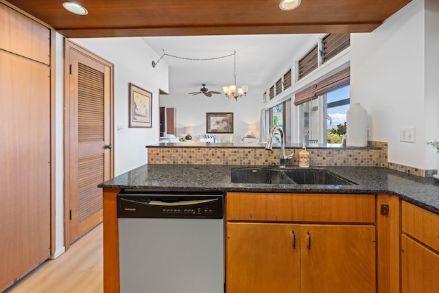 kitchen with dark stone countertops, light wood-style floors, a sink, a peninsula, and dishwashing machine