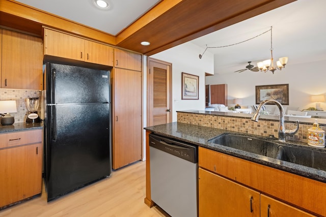 kitchen featuring tasteful backsplash, stainless steel dishwasher, a sink, freestanding refrigerator, and light wood-type flooring