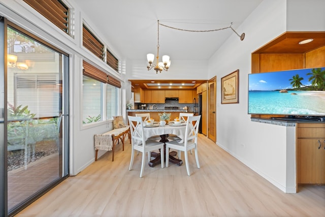 dining room with light wood finished floors, a notable chandelier, and baseboards