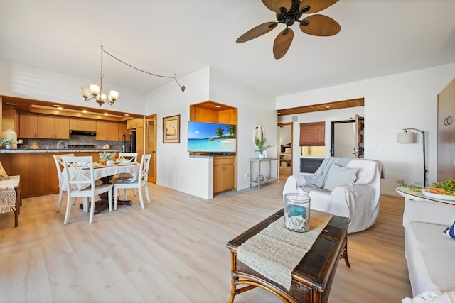 living area featuring baseboards, light wood-style flooring, and ceiling fan with notable chandelier