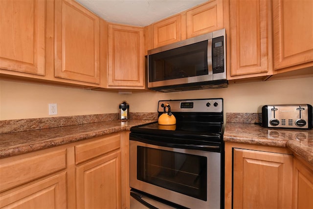 kitchen featuring light brown cabinetry, appliances with stainless steel finishes, and stone counters