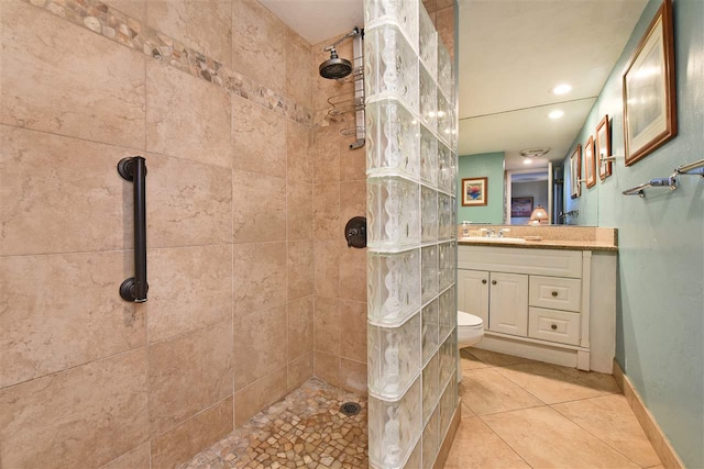 bathroom featuring tile patterned flooring, vanity, toilet, and a tile shower