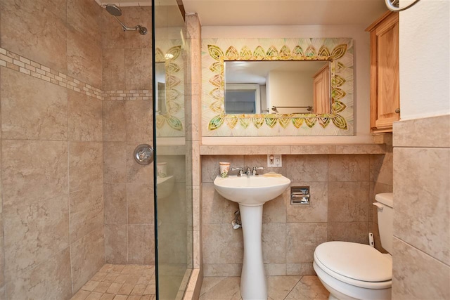 bathroom featuring tile walls, toilet, sink, and a tile shower