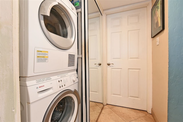 laundry room with stacked washer / dryer and light tile patterned flooring