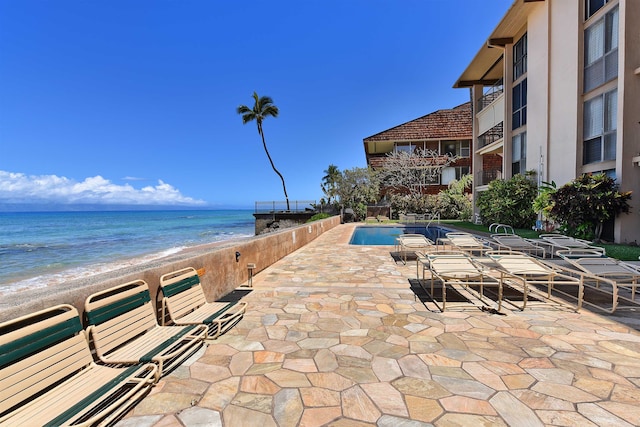 exterior space with a community pool, a beach view, a water view, and a balcony