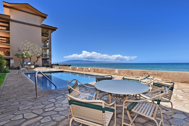 view of pool with a patio area and a water view