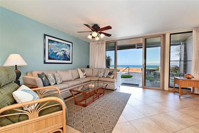 living room with ceiling fan, light tile patterned floors, a wall of windows, and a water view