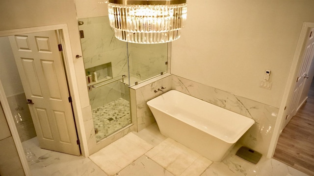 bathroom featuring separate shower and tub, tile walls, and a chandelier