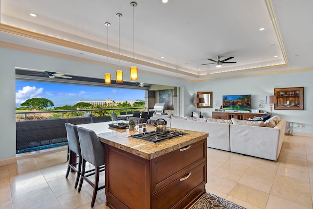 kitchen featuring a raised ceiling, a center island, stainless steel gas cooktop, decorative light fixtures, and light tile patterned flooring