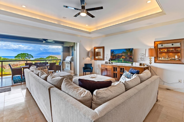 living room featuring a raised ceiling, light tile patterned flooring, and ceiling fan