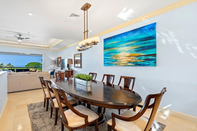 dining space with ceiling fan, a raised ceiling, crown molding, and light tile patterned floors