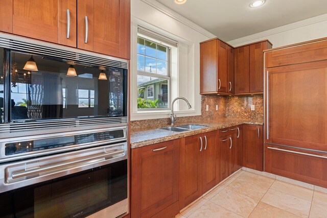 kitchen with backsplash, light stone countertops, light tile patterned floors, ornamental molding, and sink