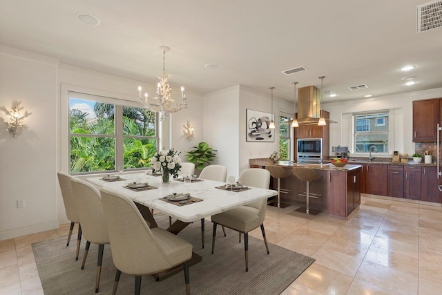 dining area featuring a notable chandelier, sink, light tile patterned floors, and crown molding