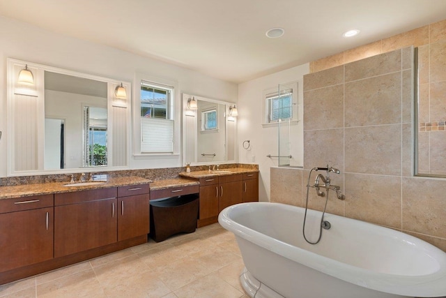 bathroom with vanity, tile walls, tile patterned flooring, and a washtub