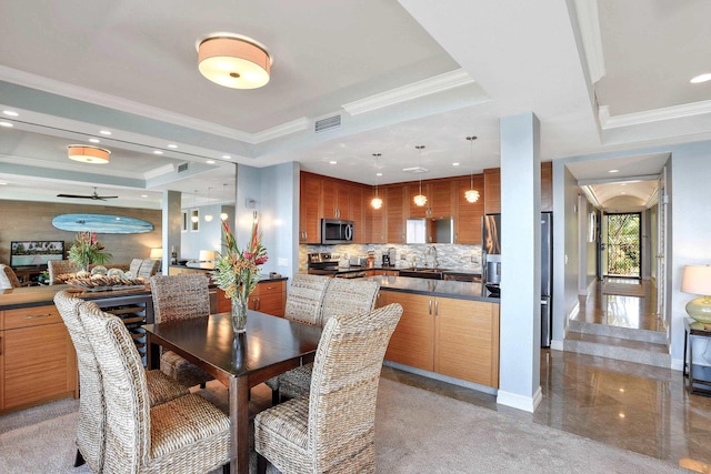 dining area with sink, ornamental molding, and a raised ceiling