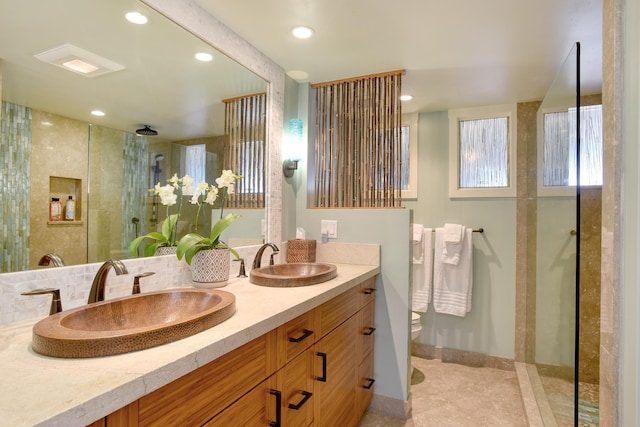 bathroom featuring tile patterned flooring, vanity, a tile shower, and toilet