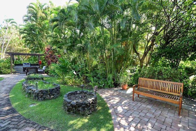 view of property's community featuring a pergola, a patio area, a lawn, and an outdoor fire pit