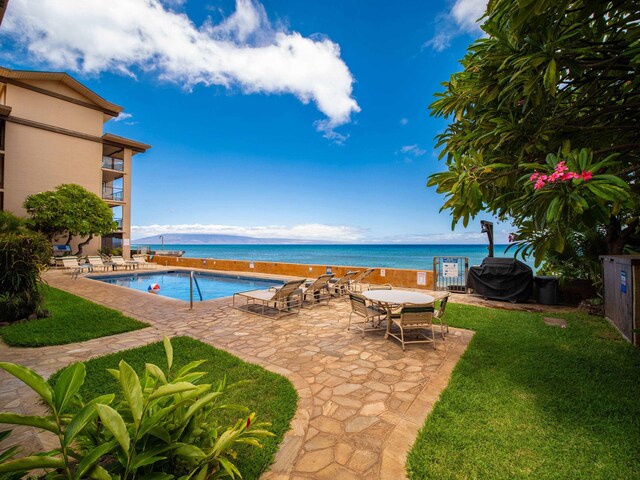 view of swimming pool with a lawn, a water view, and a patio area