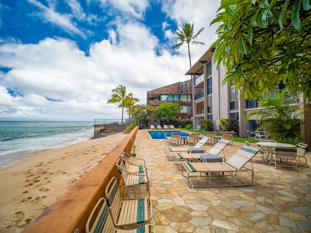 view of patio / terrace with a balcony, a beach view, a water view, and a community pool