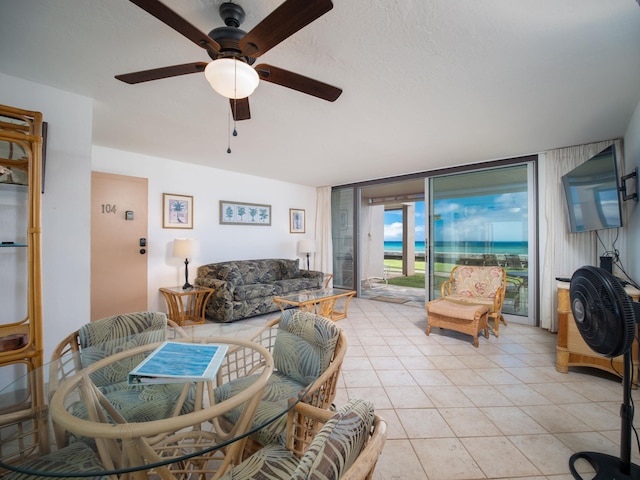 living room with ceiling fan, a wall of windows, and light tile patterned floors