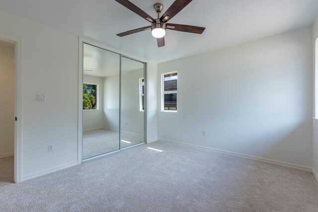 unfurnished bedroom featuring ceiling fan, light colored carpet, and a closet