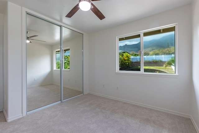 unfurnished bedroom with ceiling fan, light carpet, and a closet