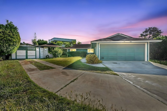 ranch-style home featuring driveway, a yard, a garage, and stucco siding