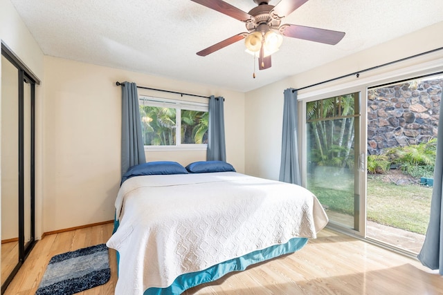 bedroom with a textured ceiling, wood finished floors, a ceiling fan, baseboards, and access to outside