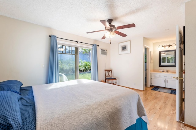 bedroom with light wood finished floors, ensuite bath, access to exterior, and a textured ceiling