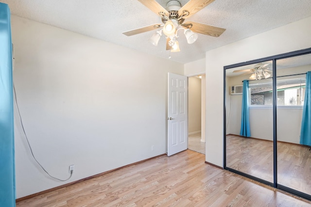 unfurnished bedroom featuring a textured ceiling, a ceiling fan, baseboards, light wood-style floors, and a closet