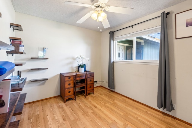 office space with light wood-style floors, a textured ceiling, baseboards, and a ceiling fan