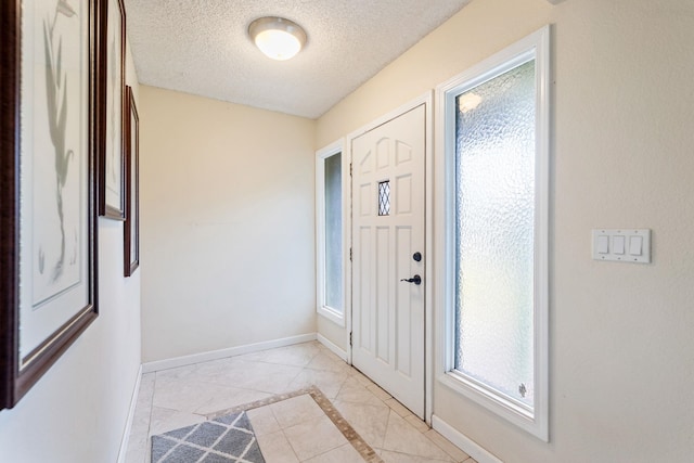 foyer entrance featuring a textured ceiling and baseboards