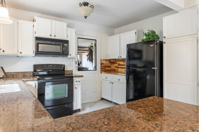 kitchen with light tile patterned floors, dark stone counters, black appliances, white cabinetry, and a sink