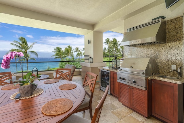 view of patio with sink, a water view, a grill, beverage cooler, and exterior kitchen