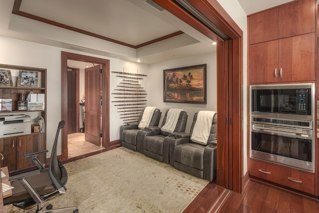 cinema featuring a raised ceiling, crown molding, and dark hardwood / wood-style flooring