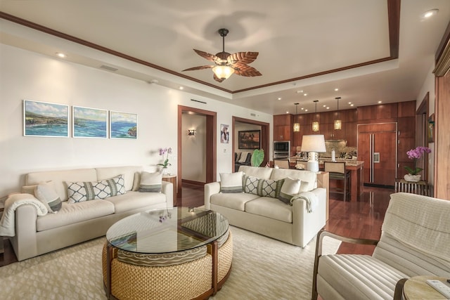 living room featuring crown molding, ceiling fan, wood-type flooring, and a tray ceiling