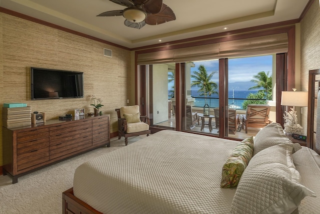 carpeted bedroom with a water view, ceiling fan, access to exterior, and a raised ceiling