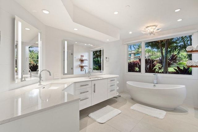 bathroom with tile patterned floors, vanity, a healthy amount of sunlight, and a tub to relax in