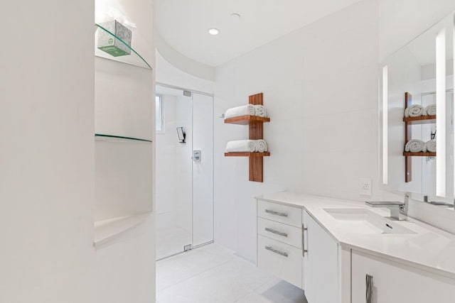 bathroom featuring vanity, tile patterned floors, a shower with door, and tile walls