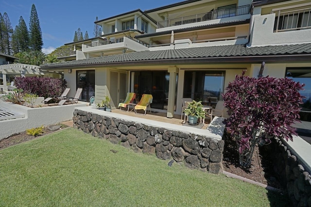 back of property with a yard and a balcony