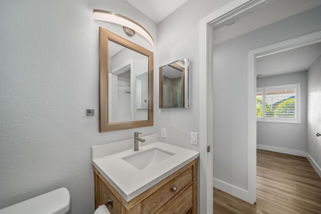 bathroom with hardwood / wood-style floors, vanity, and toilet