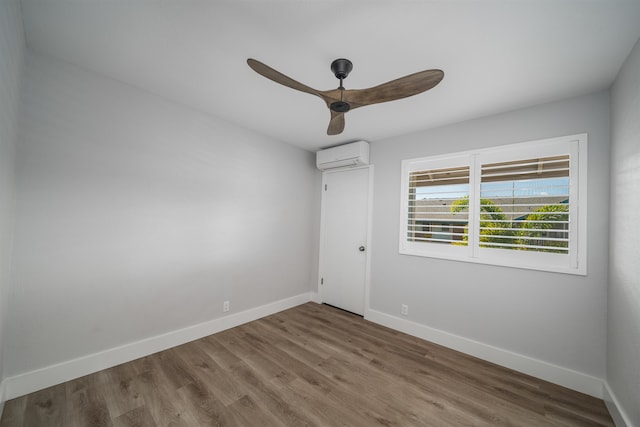 unfurnished room with ceiling fan, wood-type flooring, and a wall mounted air conditioner