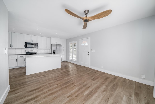 kitchen with appliances with stainless steel finishes, light wood-type flooring, ceiling fan, a center island, and white cabinetry