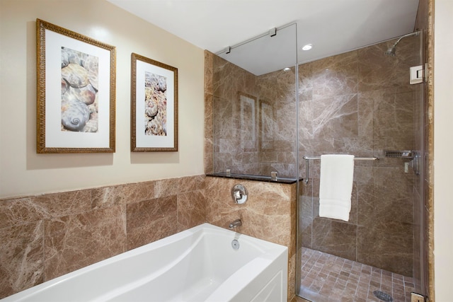 bathroom with shower with separate bathtub and tile walls