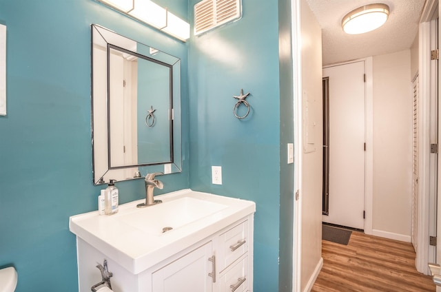 bathroom with hardwood / wood-style flooring, a textured ceiling, and vanity