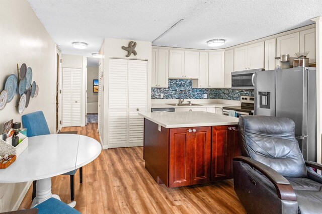 living room featuring sink, ceiling fan, light hardwood / wood-style flooring, and a textured ceiling