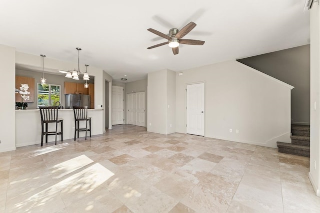 unfurnished living room with ceiling fan with notable chandelier